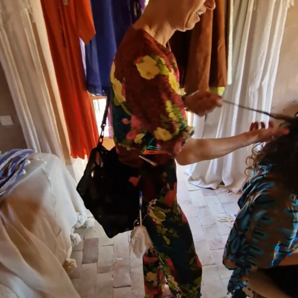 Laughing while working, surrounded by hanging Moroccan fabrics