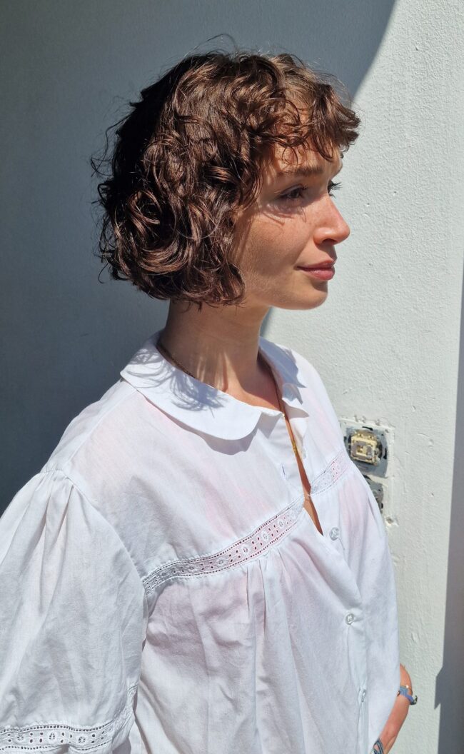 Natural portrait of a curly-haired young woman in soft daylight, white blouse — Blandine Lagoutte
