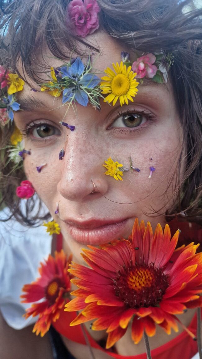 Creative flower beauty look, wildflower petals across the skin, freckles left visible — Blandine Lagoutte